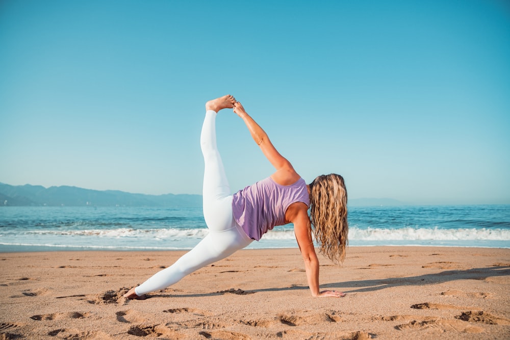 a woman doing a yoga pose on the beach