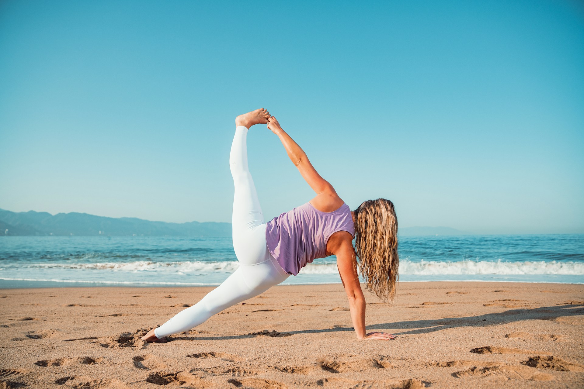 a woman doing a yoga pose on the beach