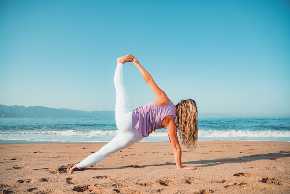 Une femme faisant une pose de yoga sur la plage
