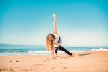 a woman doing a yoga pose on the beach