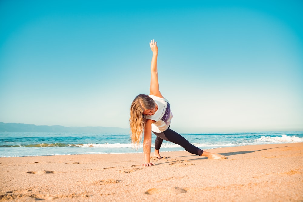 Una mujer haciendo una pose de yoga en la playa