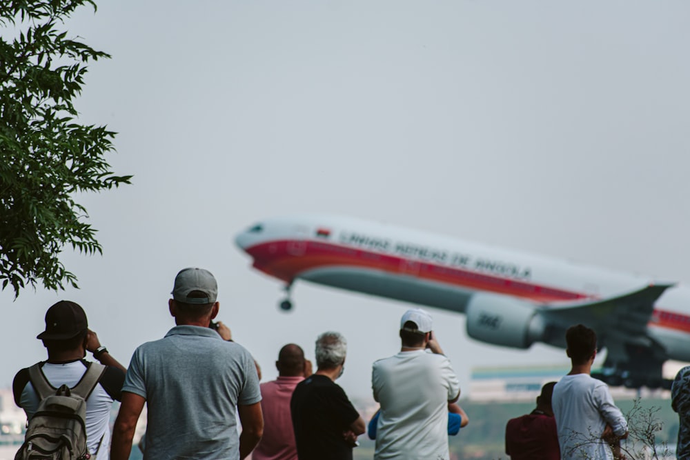 Un gruppo di persone che guardano un aereo decollare