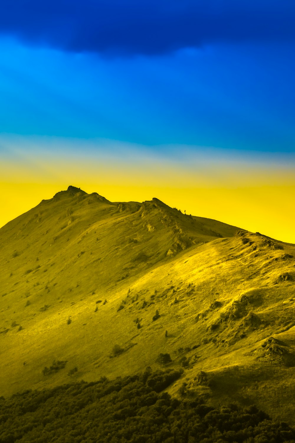 a yellow and blue sky over a mountain