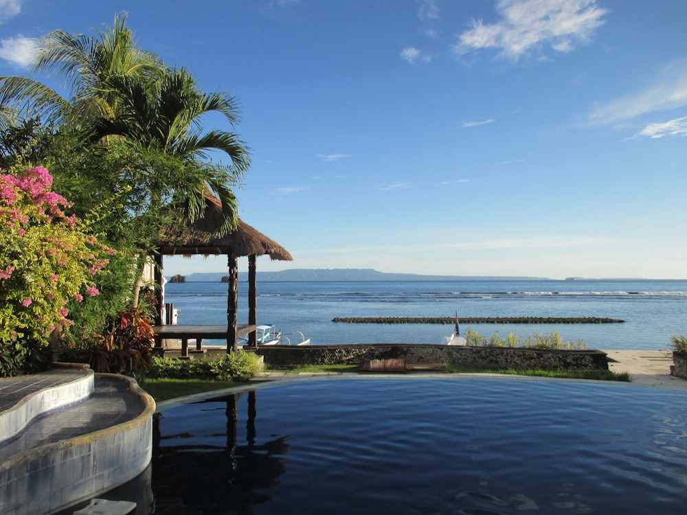 uma grande piscina com um gazebo ao lado do oceano