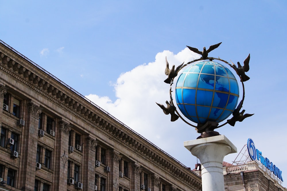 a statue of birds on top of a globe in front of a building