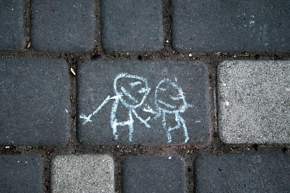 a brick sidewalk with a drawing of two people on it