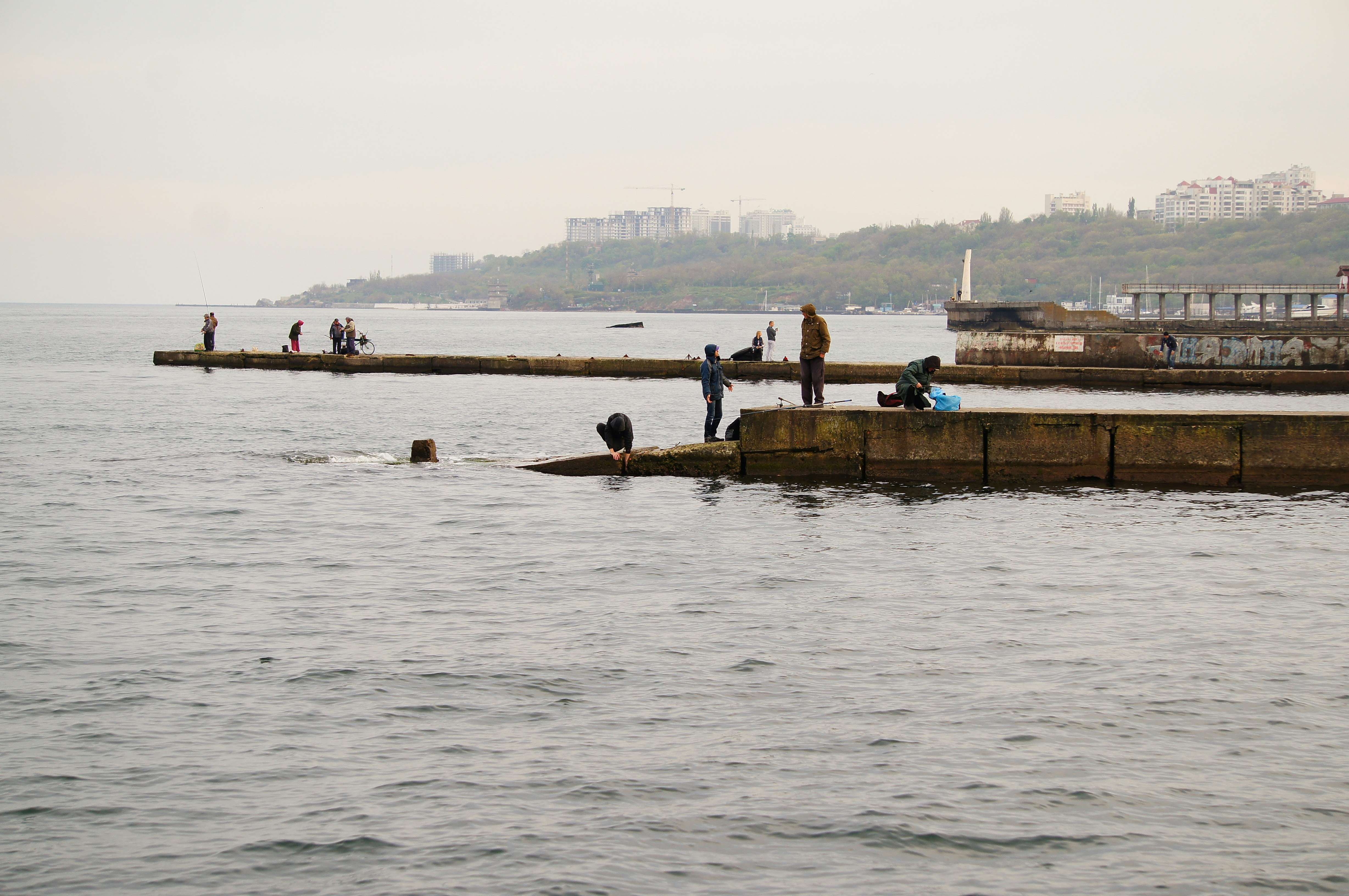 a group of people standing on a pier next to the ocean
