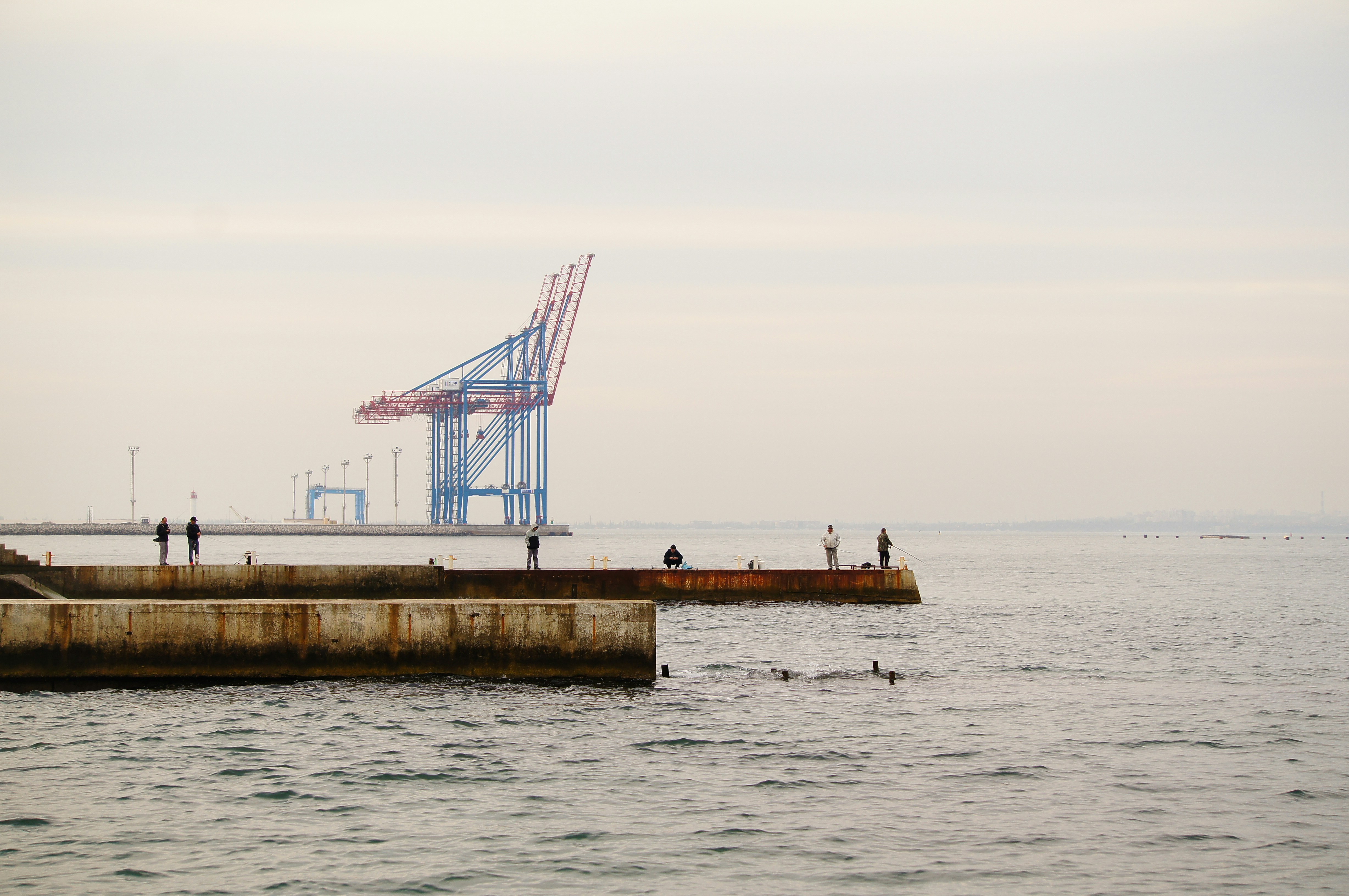 a group of people standing on top of a pier next to the ocean