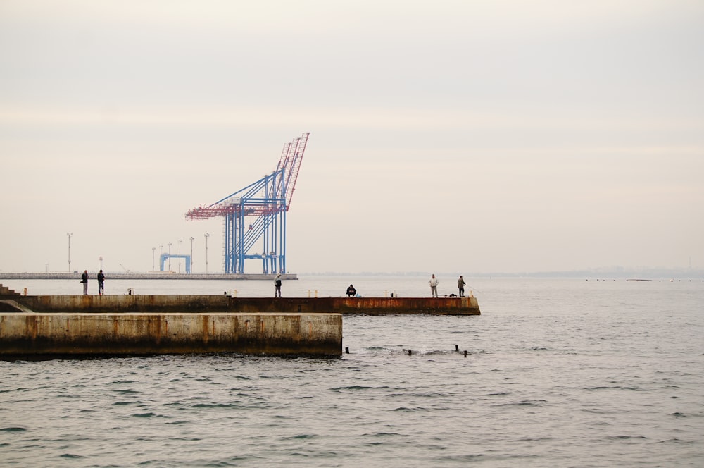 a group of people standing on top of a pier next to the ocean