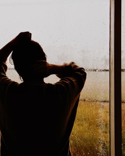 a man standing in front of a window covered in rain