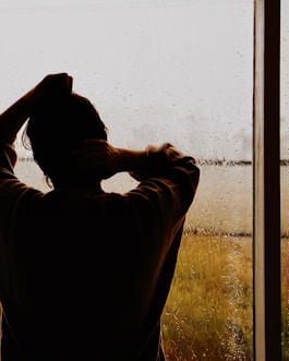 a man standing in front of a window covered in rain