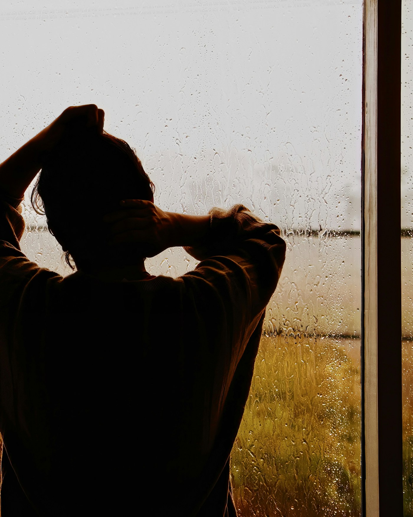 Hombre de pie delante de una ventana con lluvia