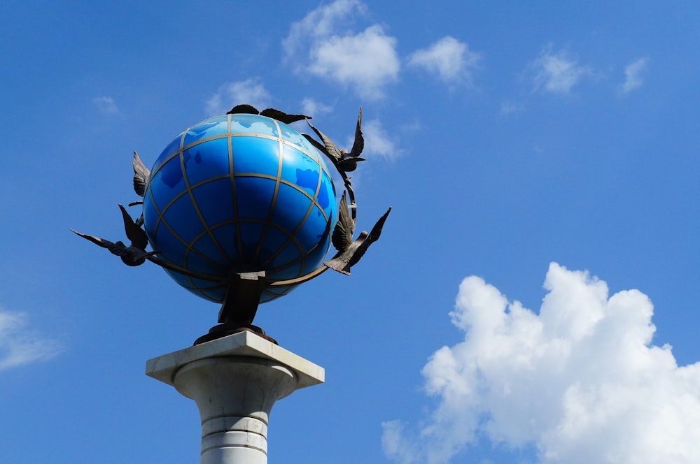a blue globe with birds on top of it