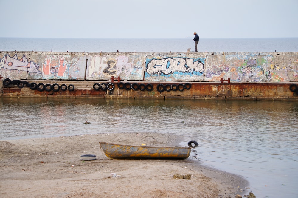 a man standing on a wall next to a body of water