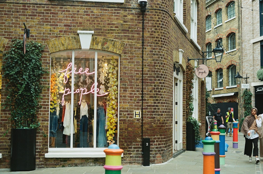 a woman walking down a street past a store front