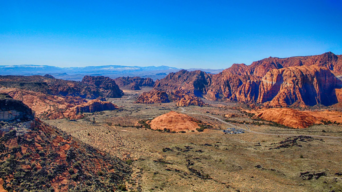 Red sandstone cliffs and a desert valley in Snow Canyon, north of St. George, with snowy mountains far off