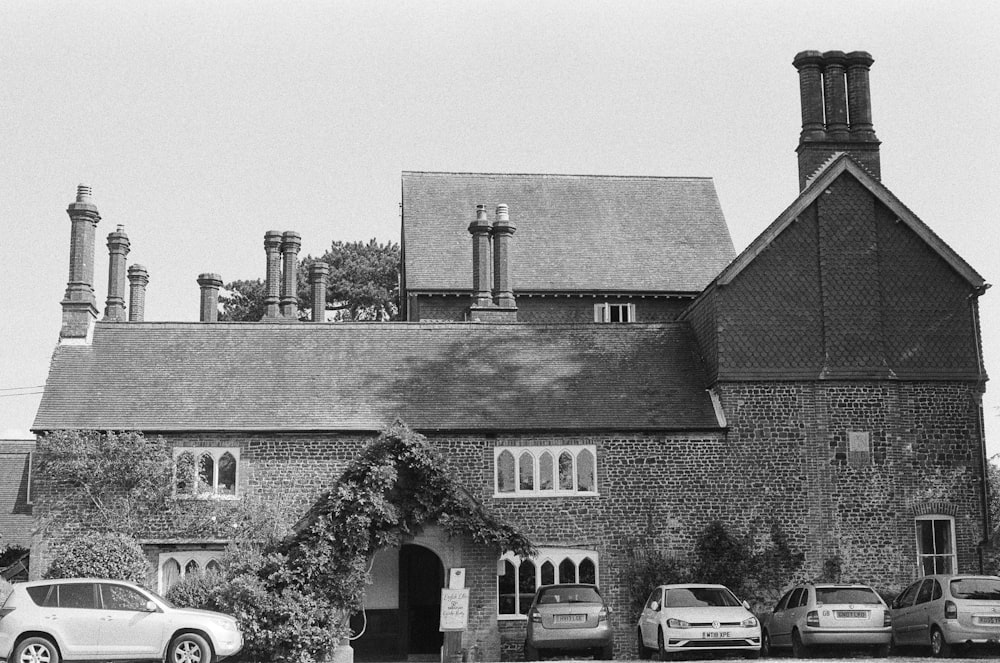 a black and white photo of a building with cars parked in front of it