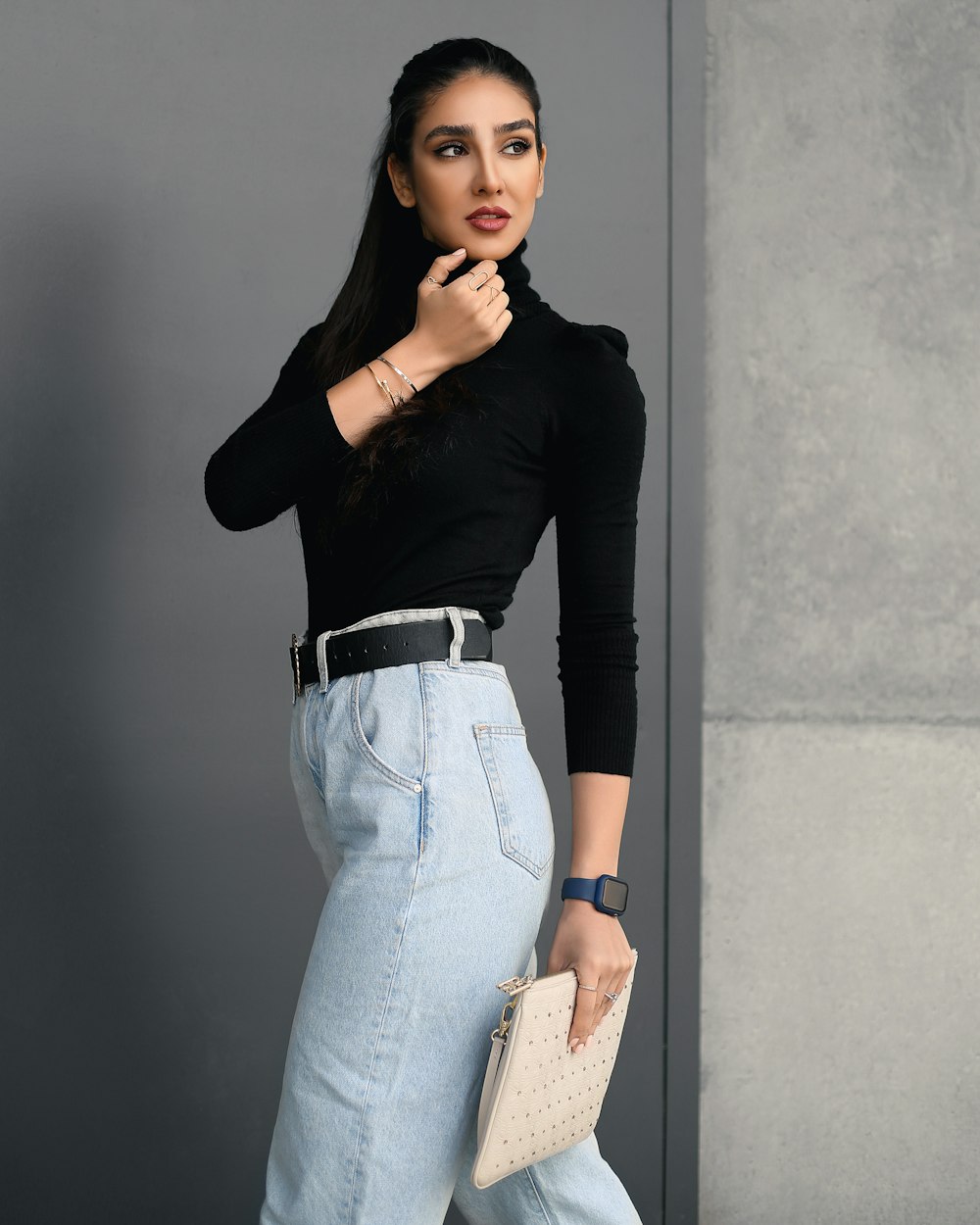 a woman in black shirt and jeans holding a white purse