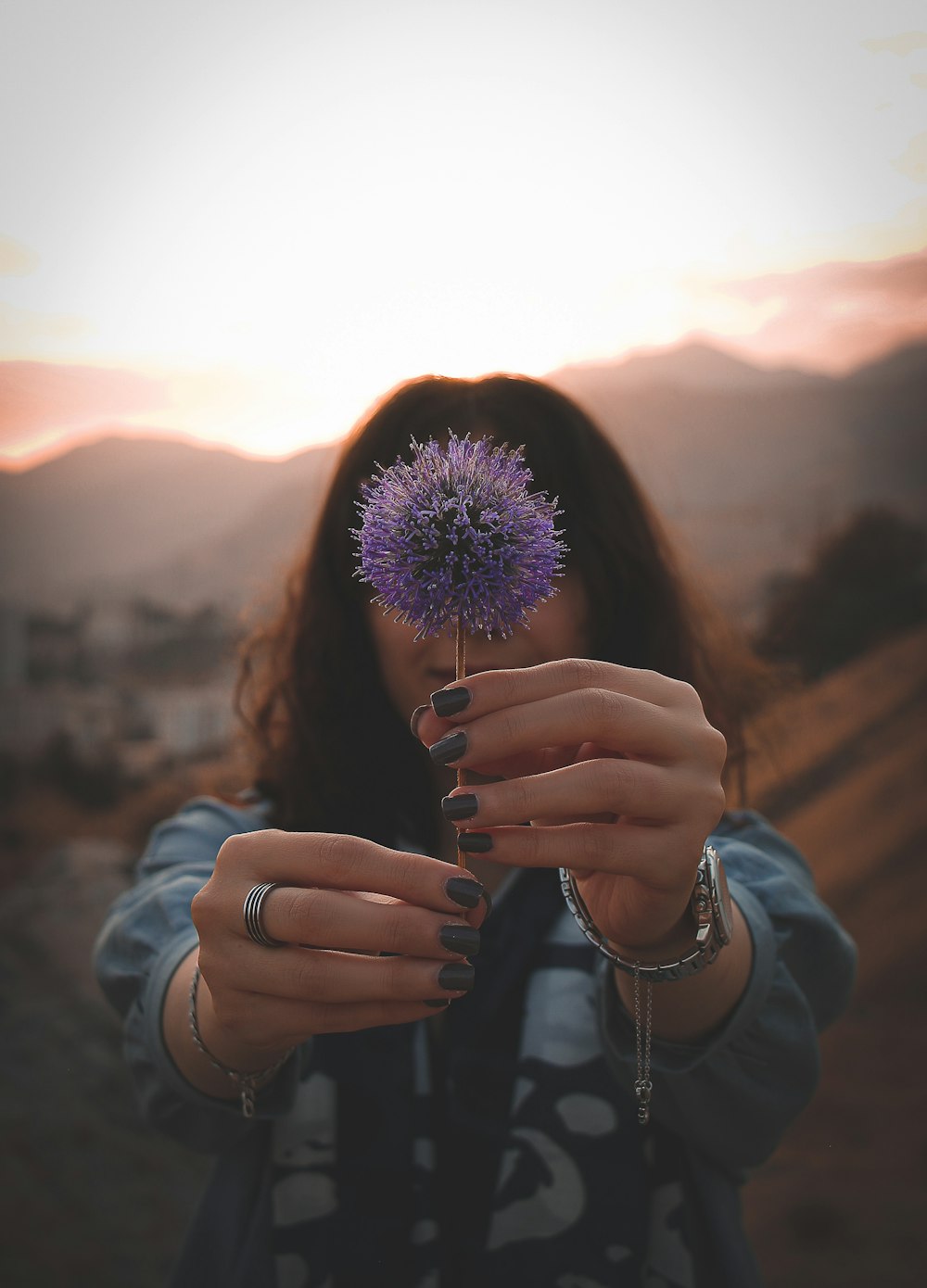 a woman holding a purple flower in her hands