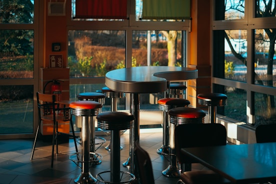 a restaurant with tables and stools in front of a large window