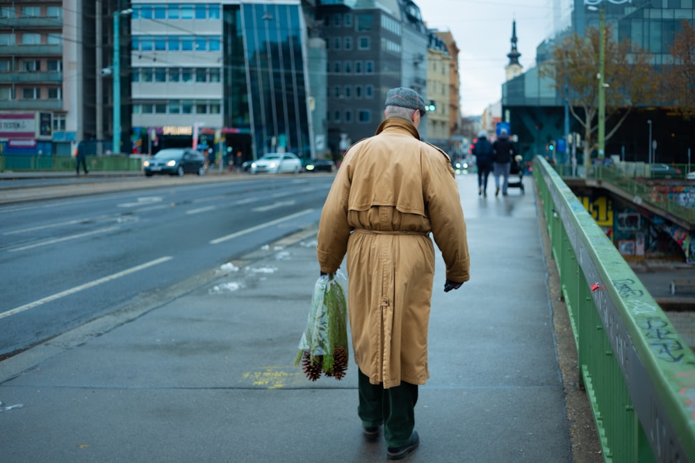 a man in a trench coat walking down a street