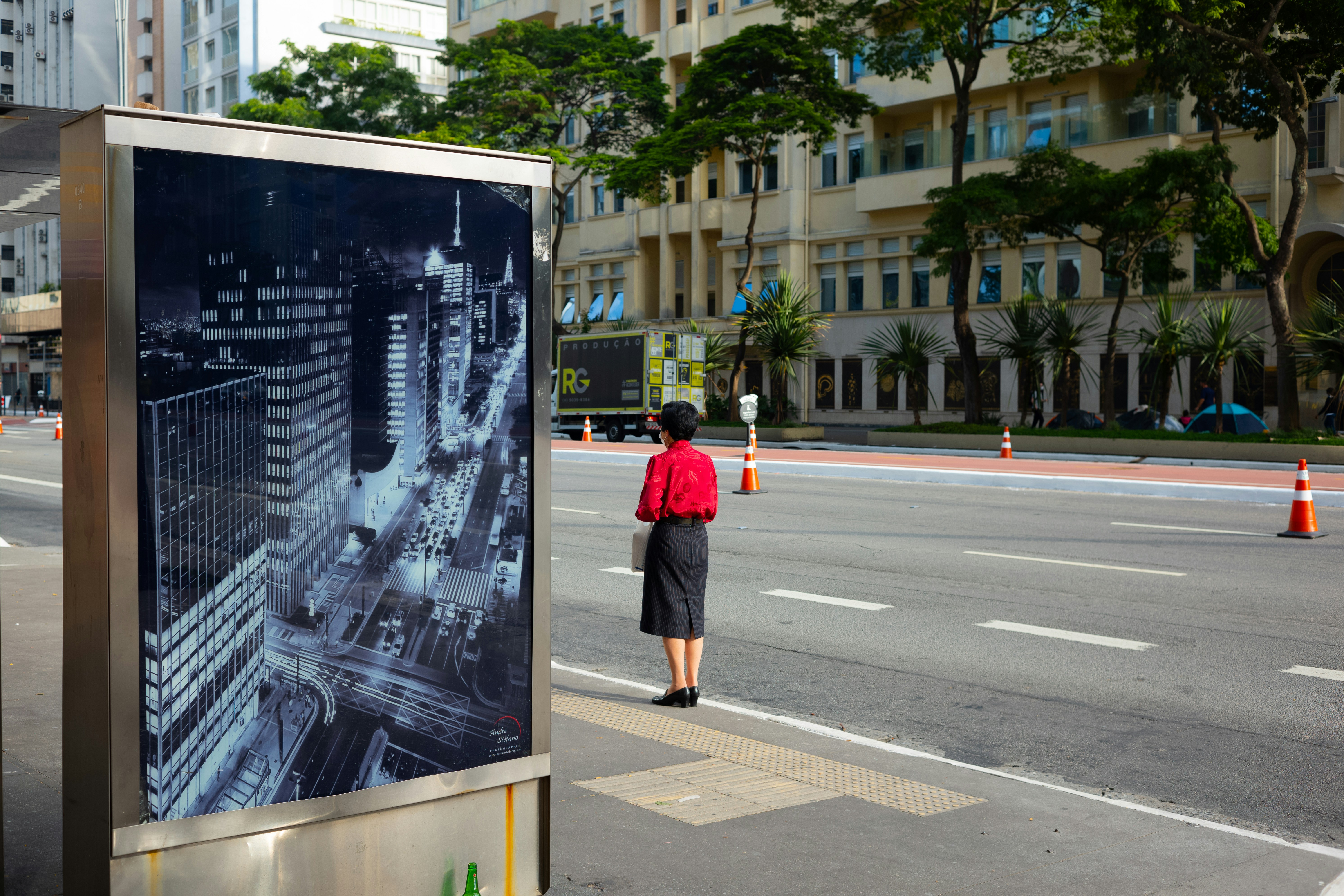a woman in a red shirt is standing at a bus stop