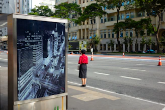 a woman in a red shirt is standing at a bus stop