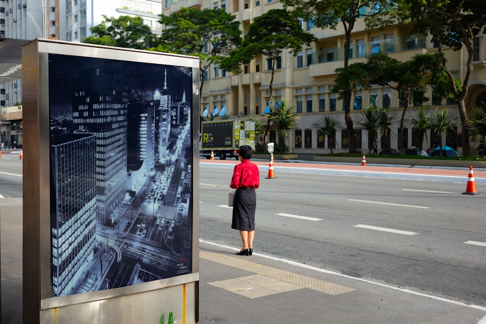 a woman in a red shirt is standing at a bus stop