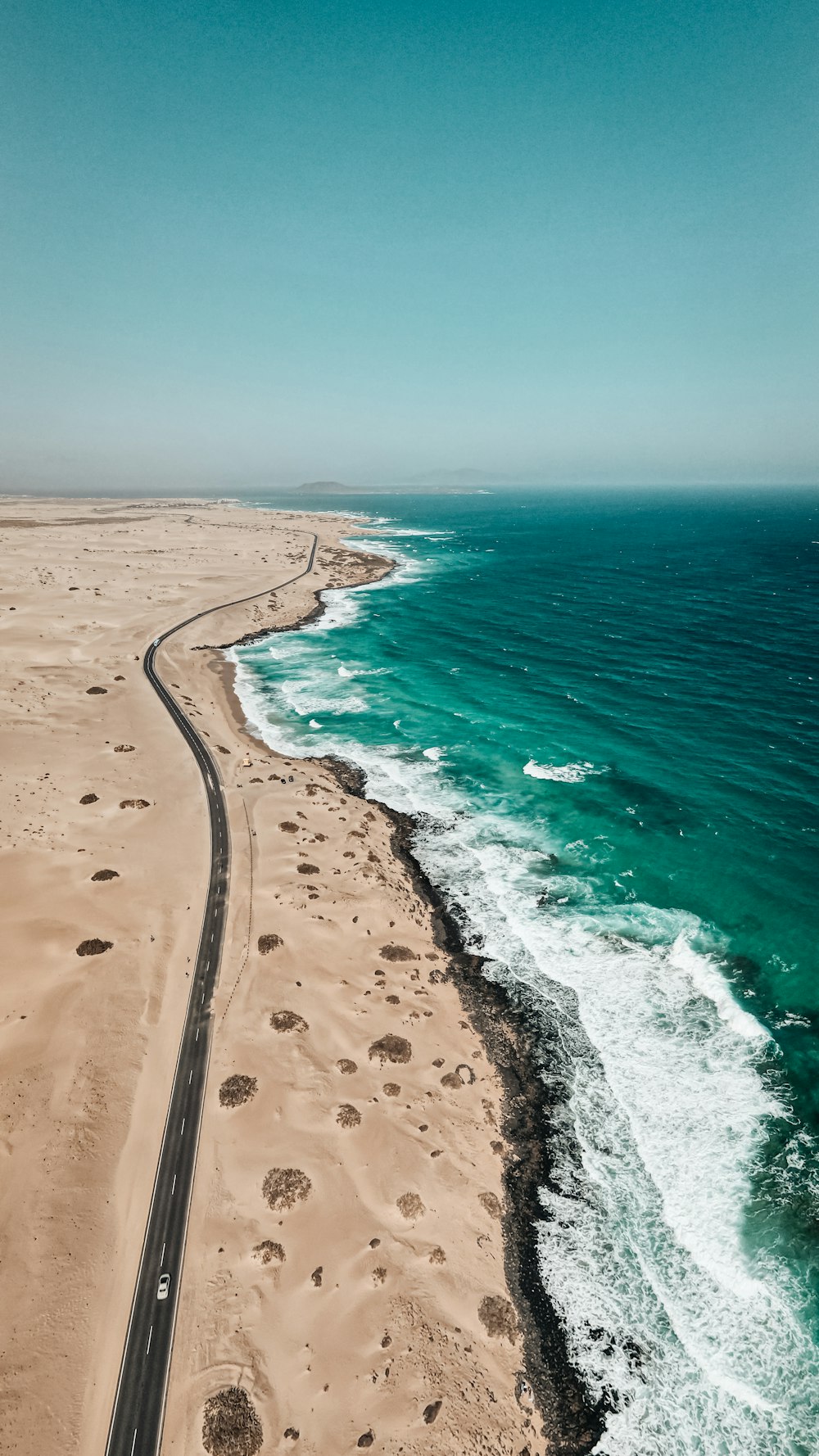 an aerial view of a road running along the beach