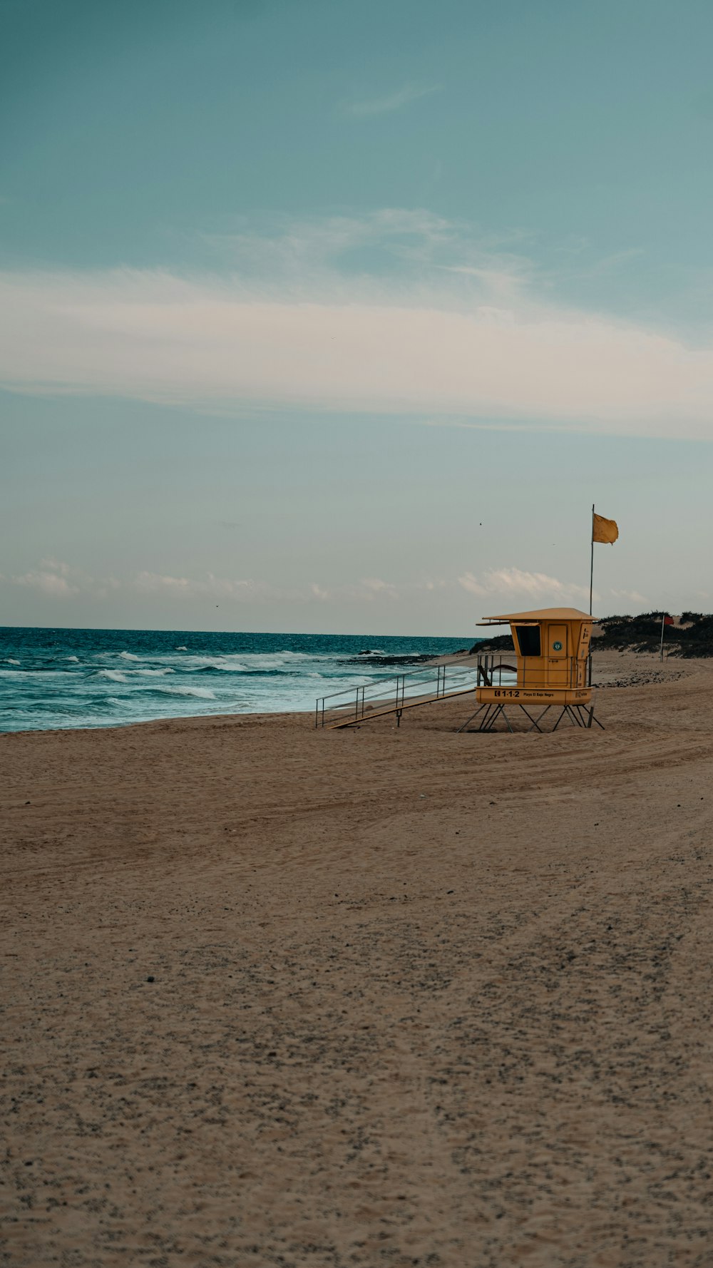 a lifeguard station on the beach with a flag flying