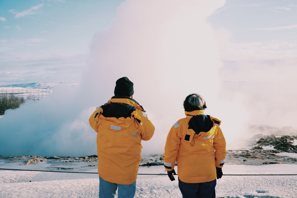 two people standing in front of a geyser