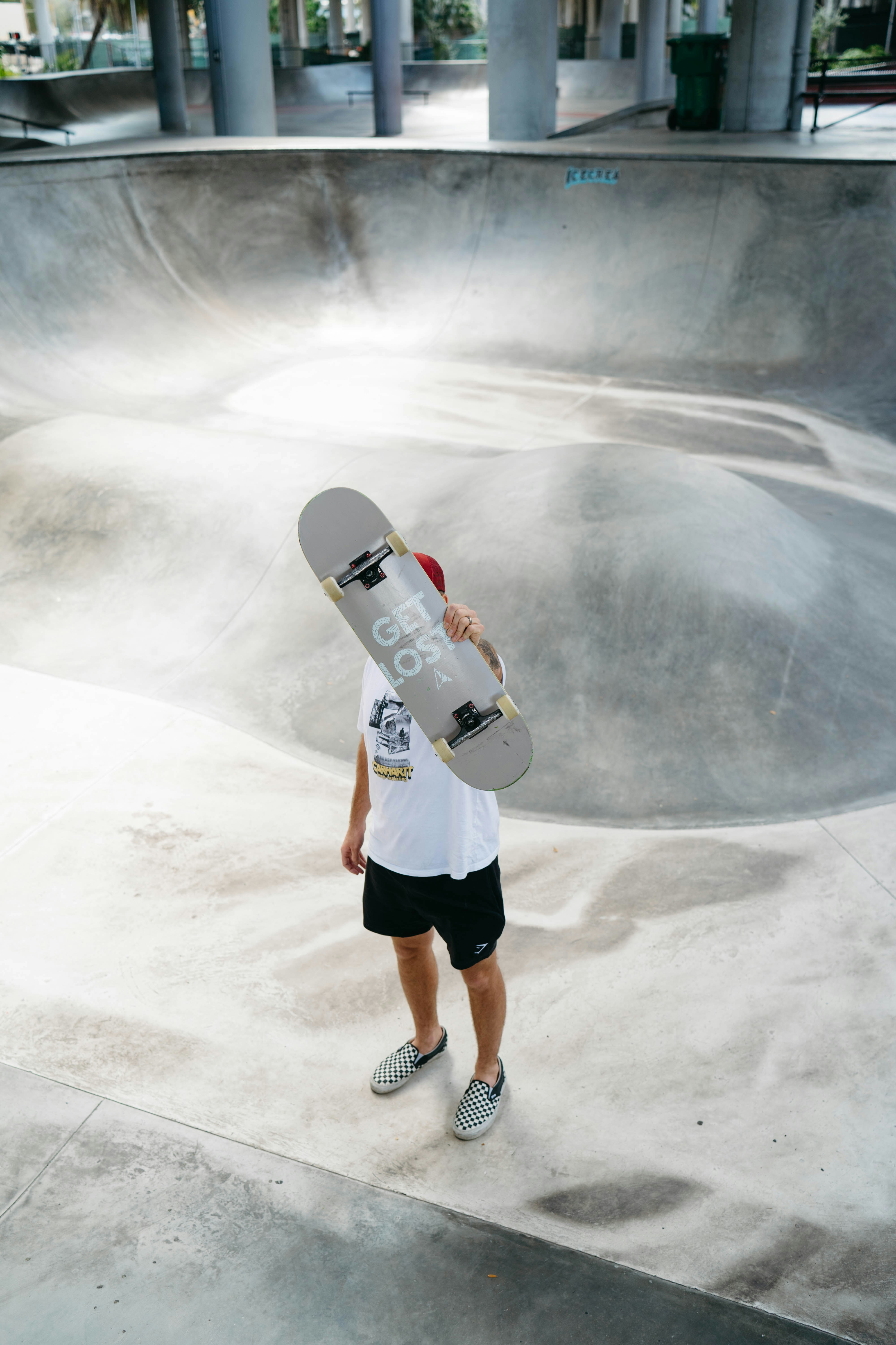 Seorang pria memegang skateboard di taman skate