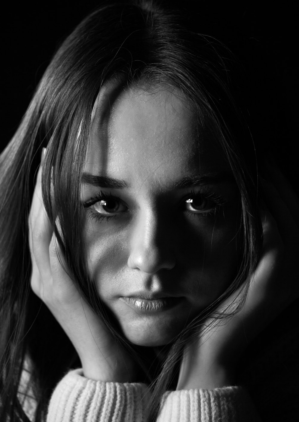 a black and white photo of a woman with her hands on her head