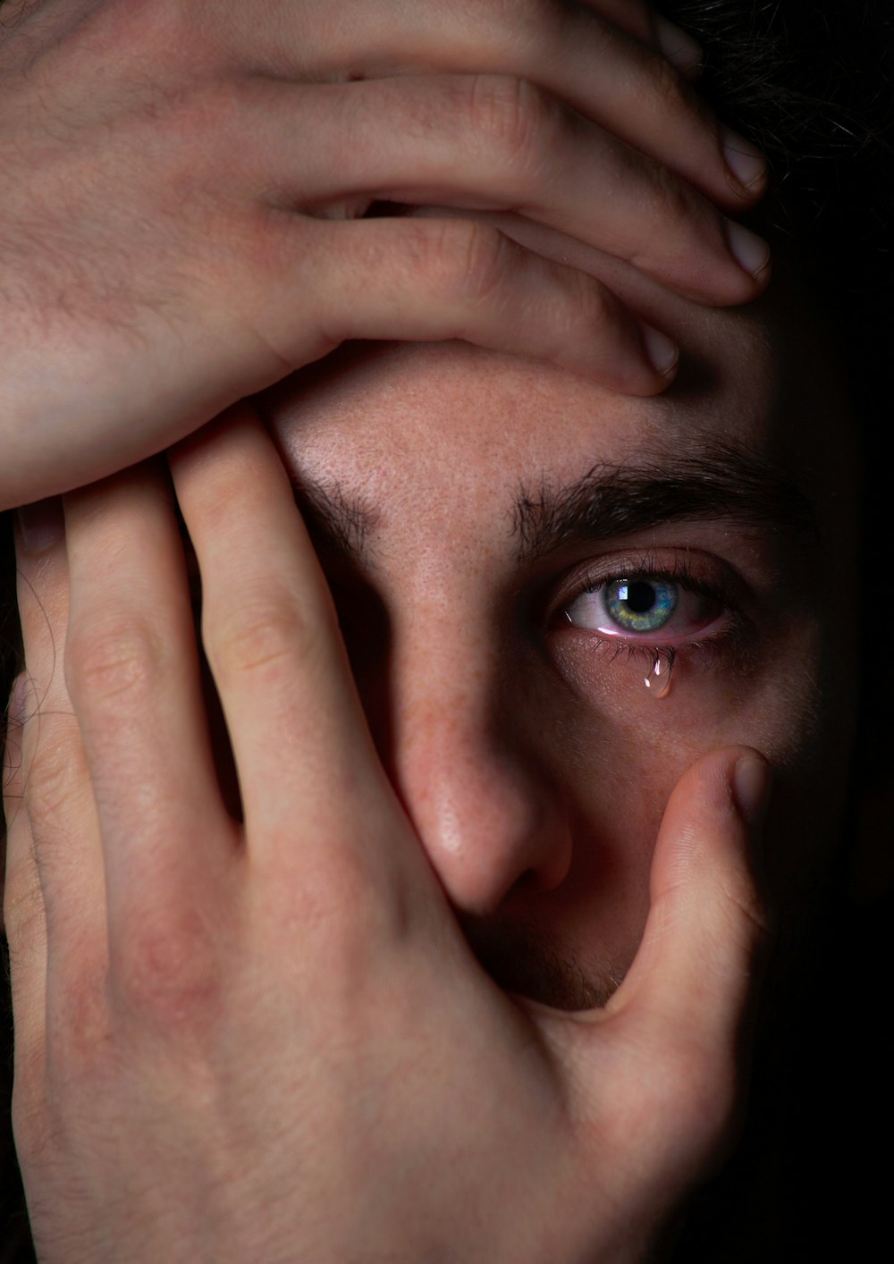 a close up of a person covering their face with their hands