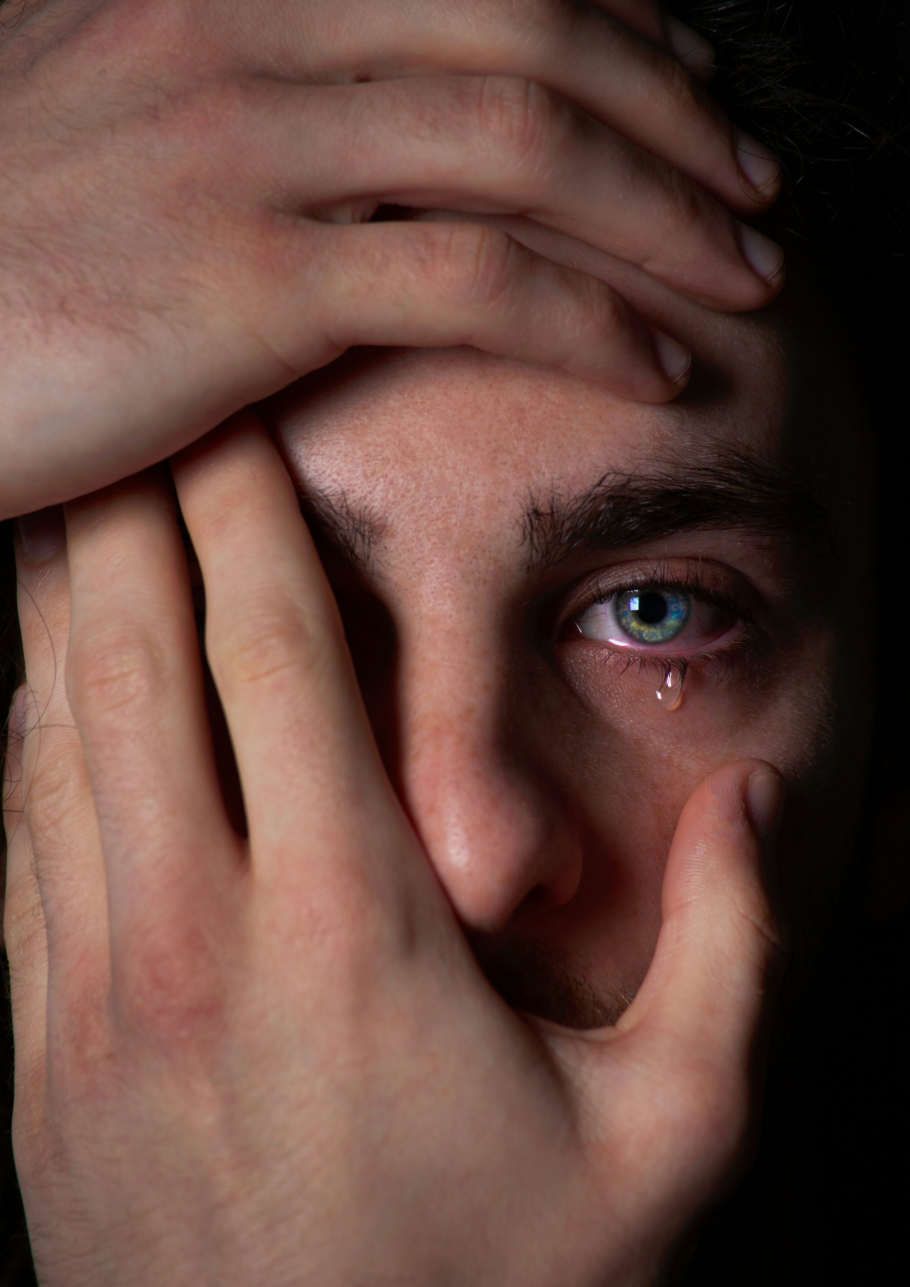 a close up of a person covering their face with their hands