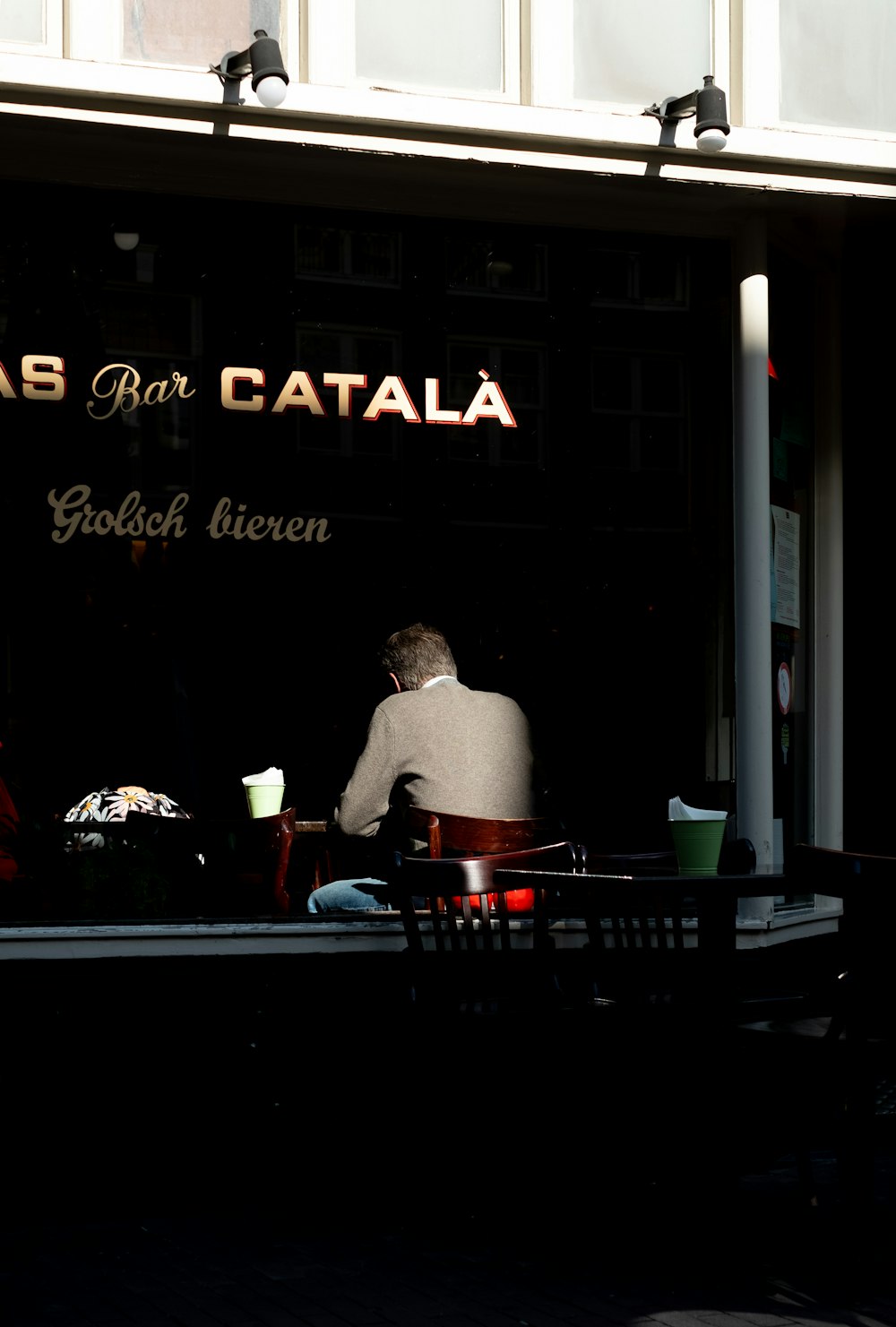 a man sitting at a table outside of a restaurant