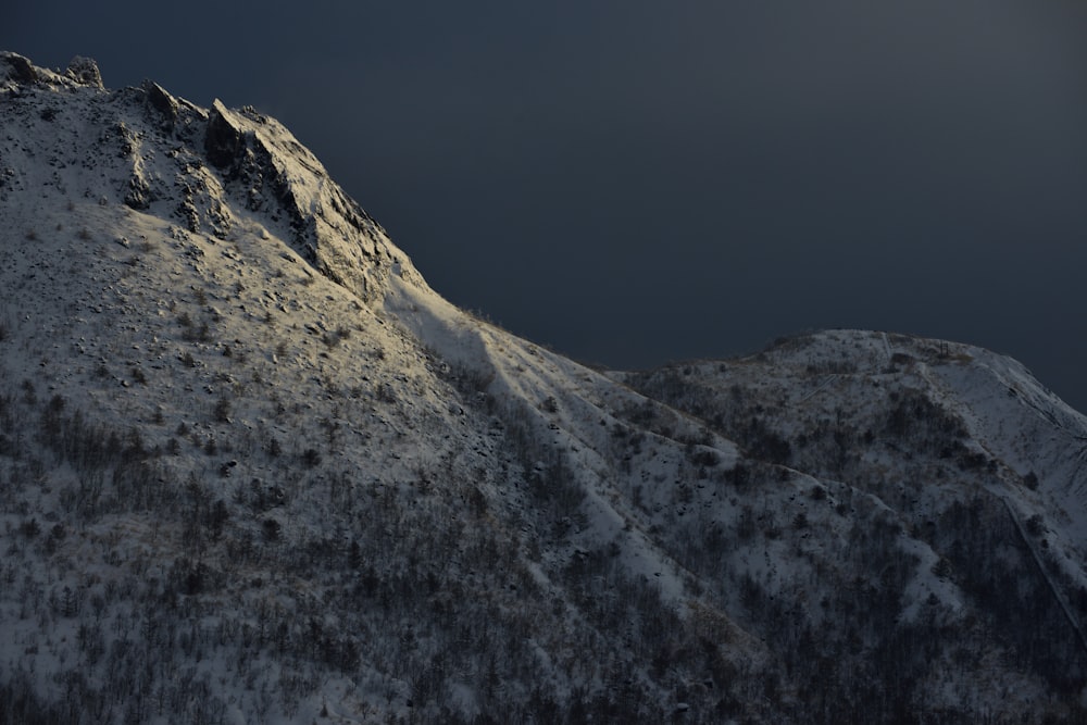 a mountain covered in snow under a dark sky