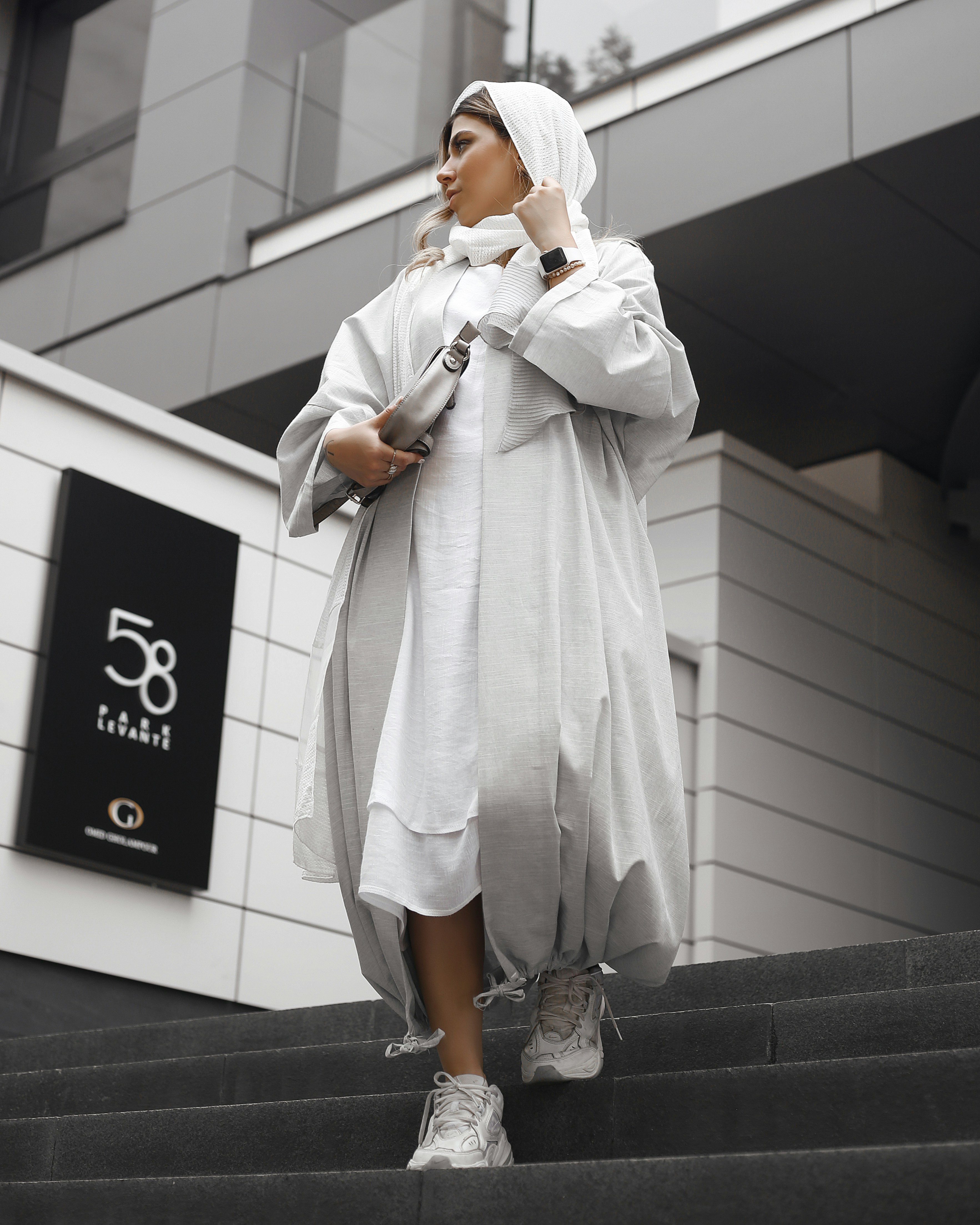 Seorang wanita berjubah putih sedang berjalan menuruni tangga