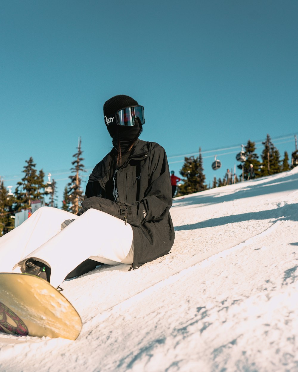 a snowboarder sitting on the snow with his board
