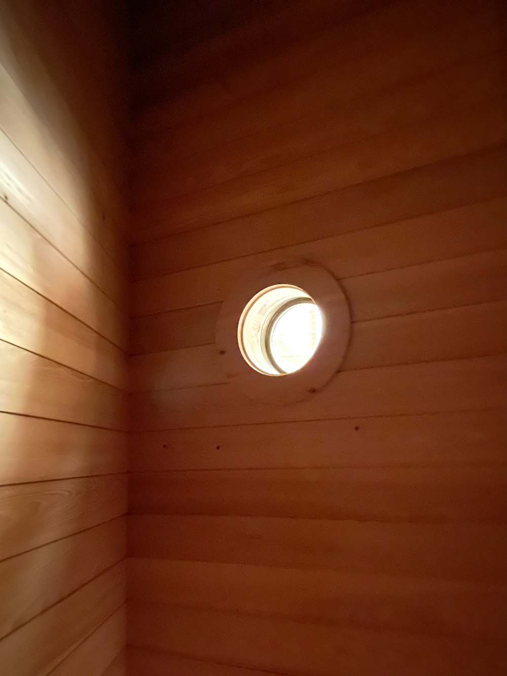 a small round window in a wooden wall