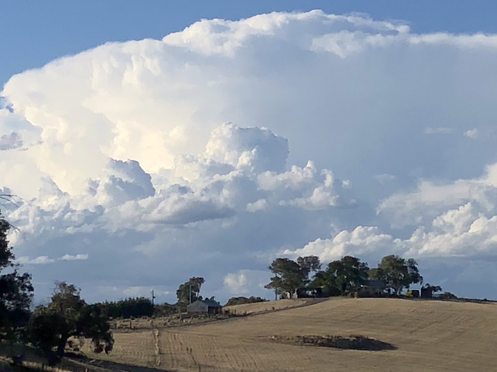 a large cloud is in the sky over a field