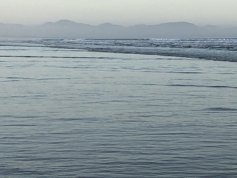 a person walking on the beach with a surfboard