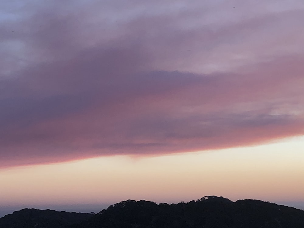 a plane flying in the sky with a mountain in the background