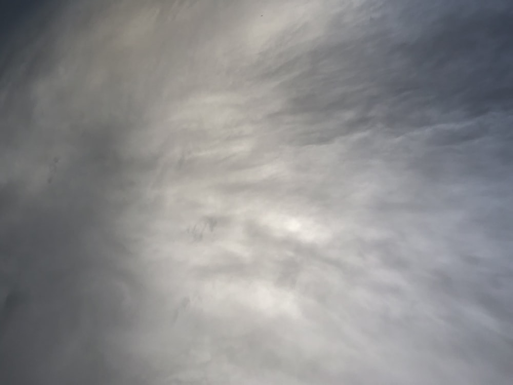 a plane flying through a cloudy blue sky