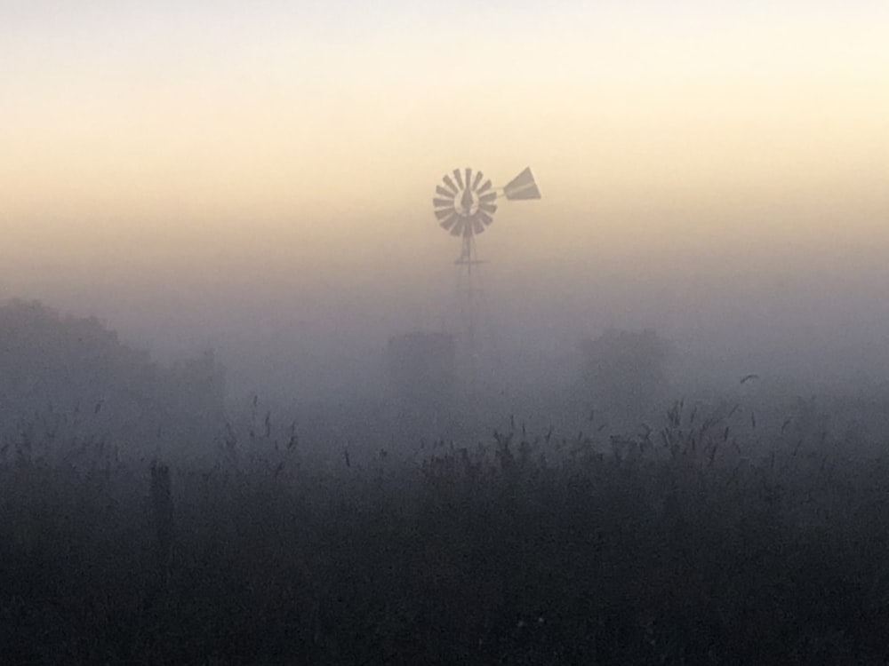 a foggy field with a windmill in the distance
