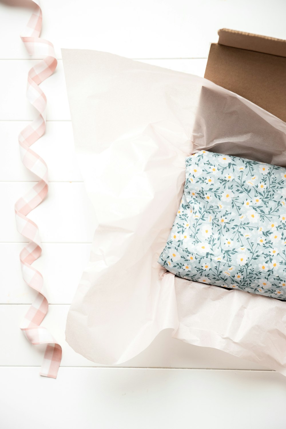 a box with a blue and white pillow and a pink ribbon