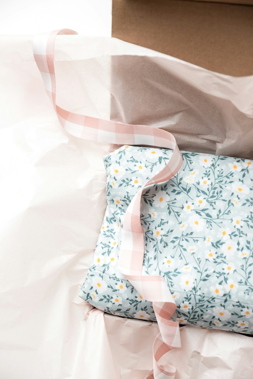 a box with a pink ribbon and a blue and white pillow