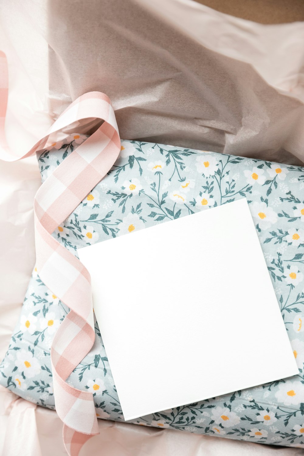 a blank card on a pillow with a pink ribbon