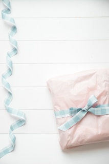 a pink wrapped present with a blue ribbon, personalized gift idea
