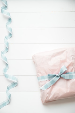 a pink wrapped present with a blue ribbon, personalized gift idea